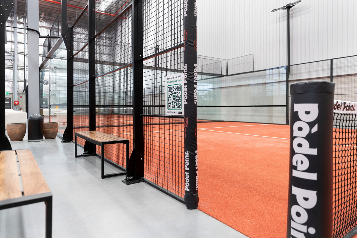 Indoor padel court with a terracotta surface, black mesh walls and a Padel Point post at the Bankstown club