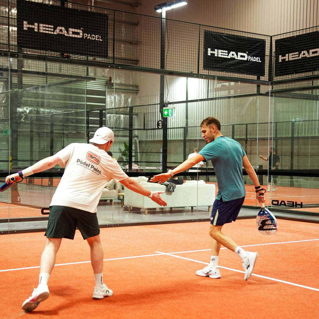 Large group of players posing together at the net on an indoor padel court at Padel Point