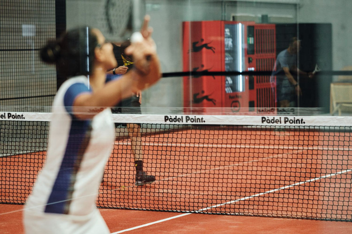 Player preparing to serve at the net on an indoor padel court at Padel Point